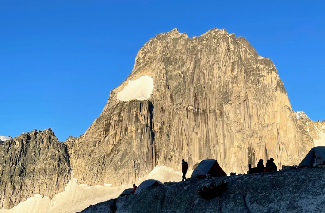 Tents and campers silhouetted in the evening light against Snowpatch Spire.