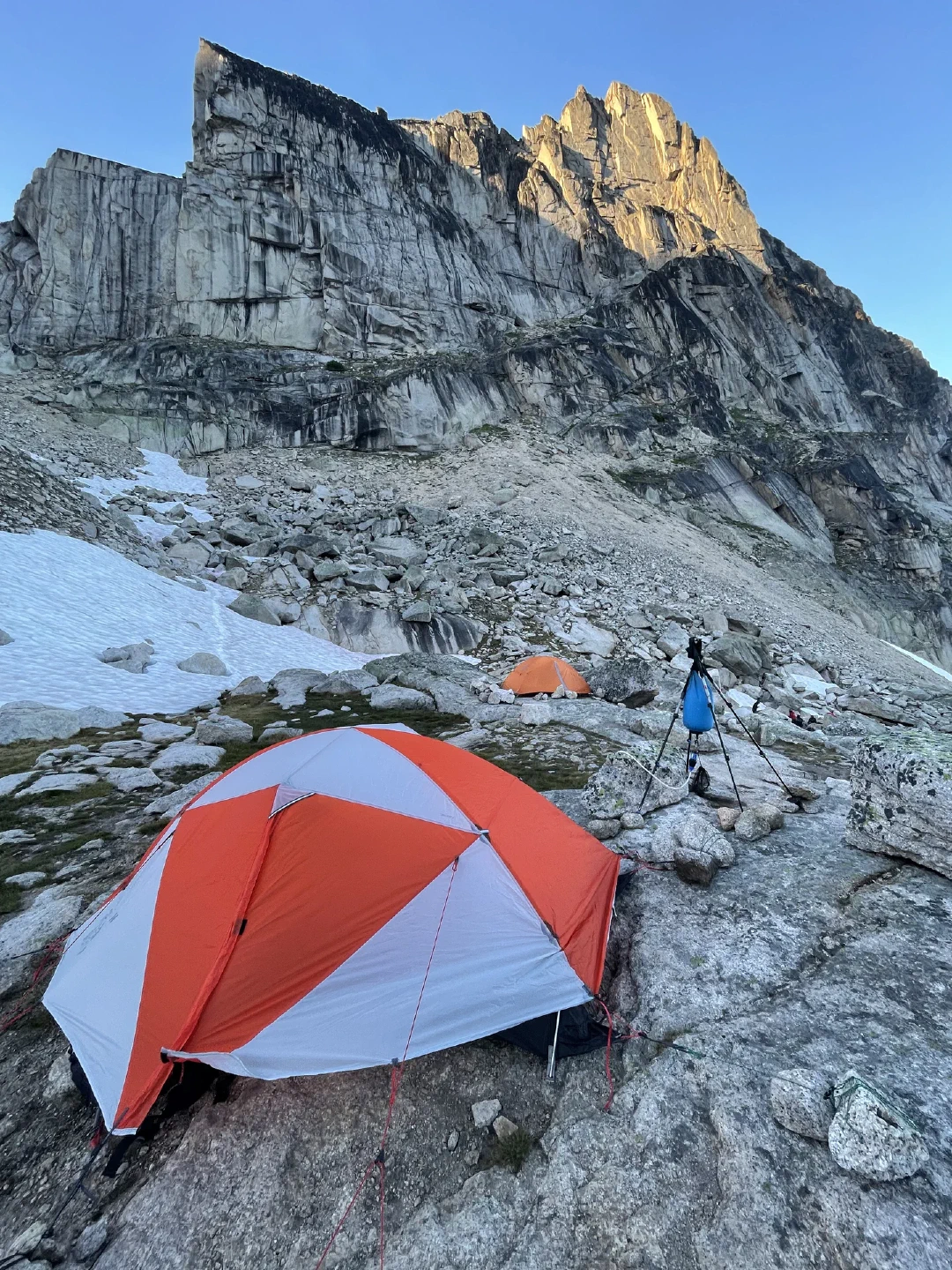 Tents pitched on granite at dusk, a gravity water filter rigged on trekking poles