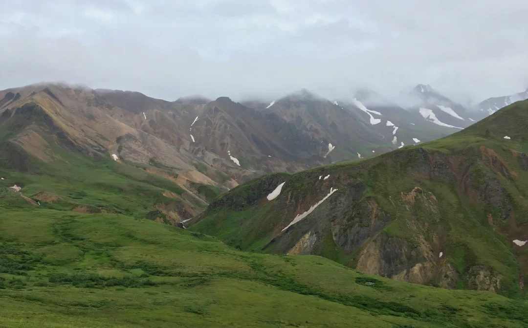Green folds of tundra rising to weathered peaks lost in low cloud.