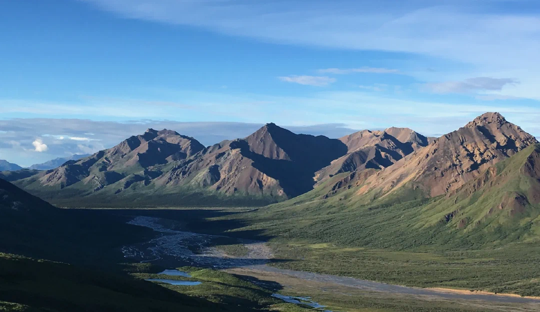 Evening light on bare peaks above a braided river valley.