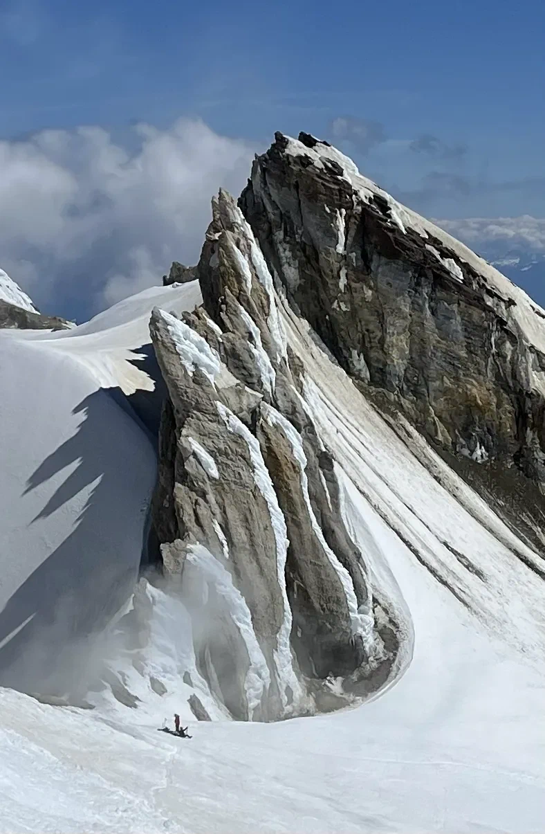 A lone skier beneath the Sherman Peak fin, on the crater edge.