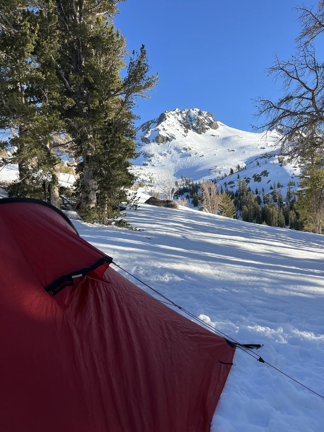 Red tent pitched on snow, Round Top’s summit rising above.