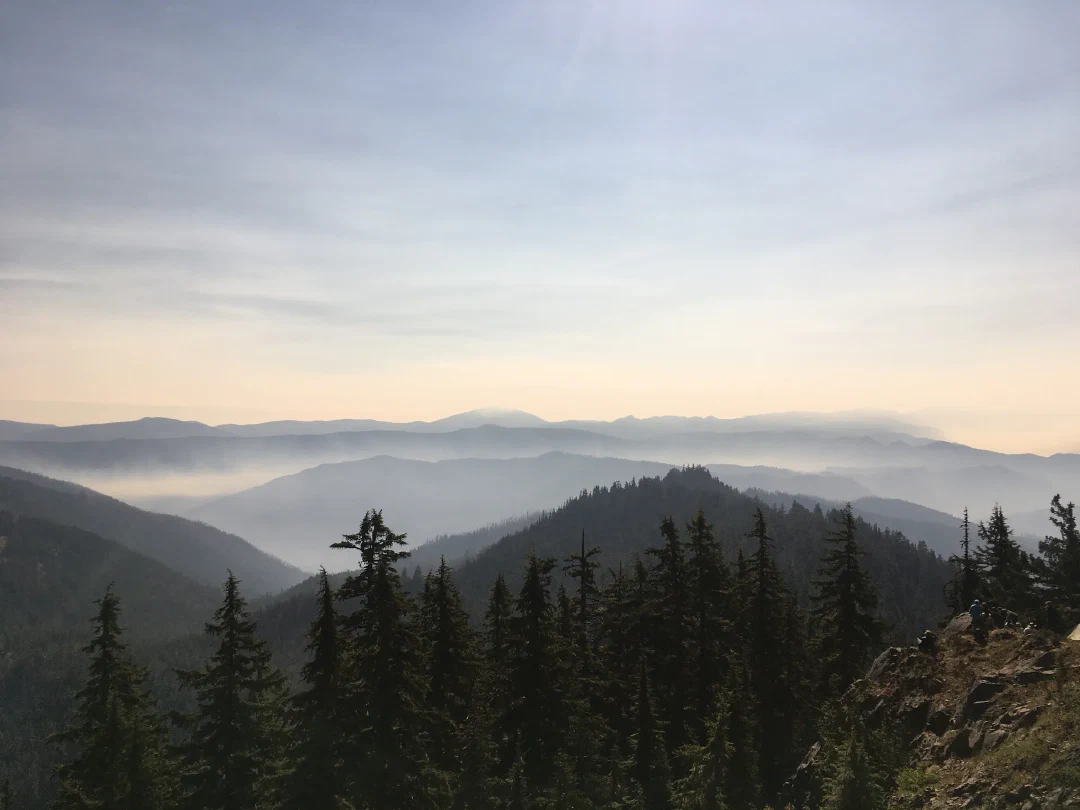 Smoke pooled in the valleys under a paling sky in the last minutes before totality.