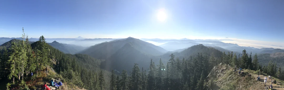 Panorama from the lookout, smoky ridgelines in every direction and eclipse-watchers settled along the rocks