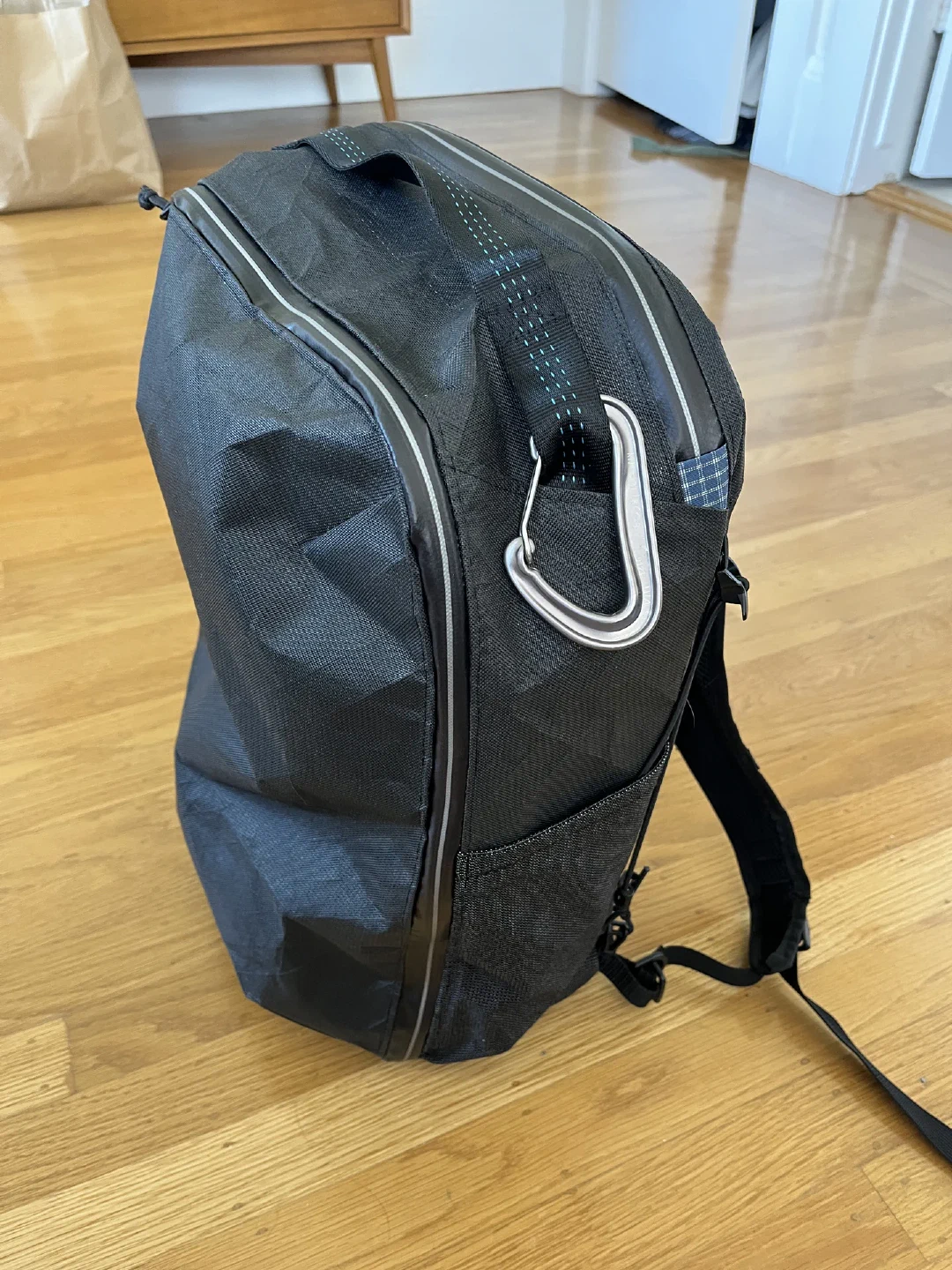 The finished black pack standing upright, a carabiner clipped to the top handle.