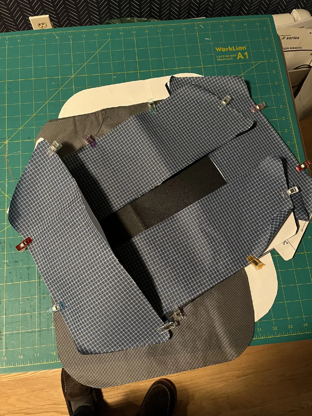 Paper pattern pieces pinned to blue gridstop fabric on a cutting mat.