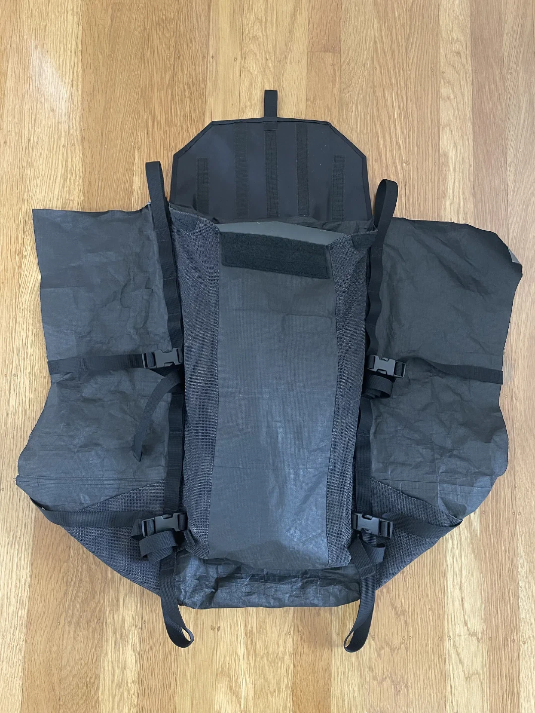 Daisy chains with tool loops, compression straps, and pocket flap attached to front pocket and main body side walls. Tip of avalanche shovel blade peeking out of pocket for scale.