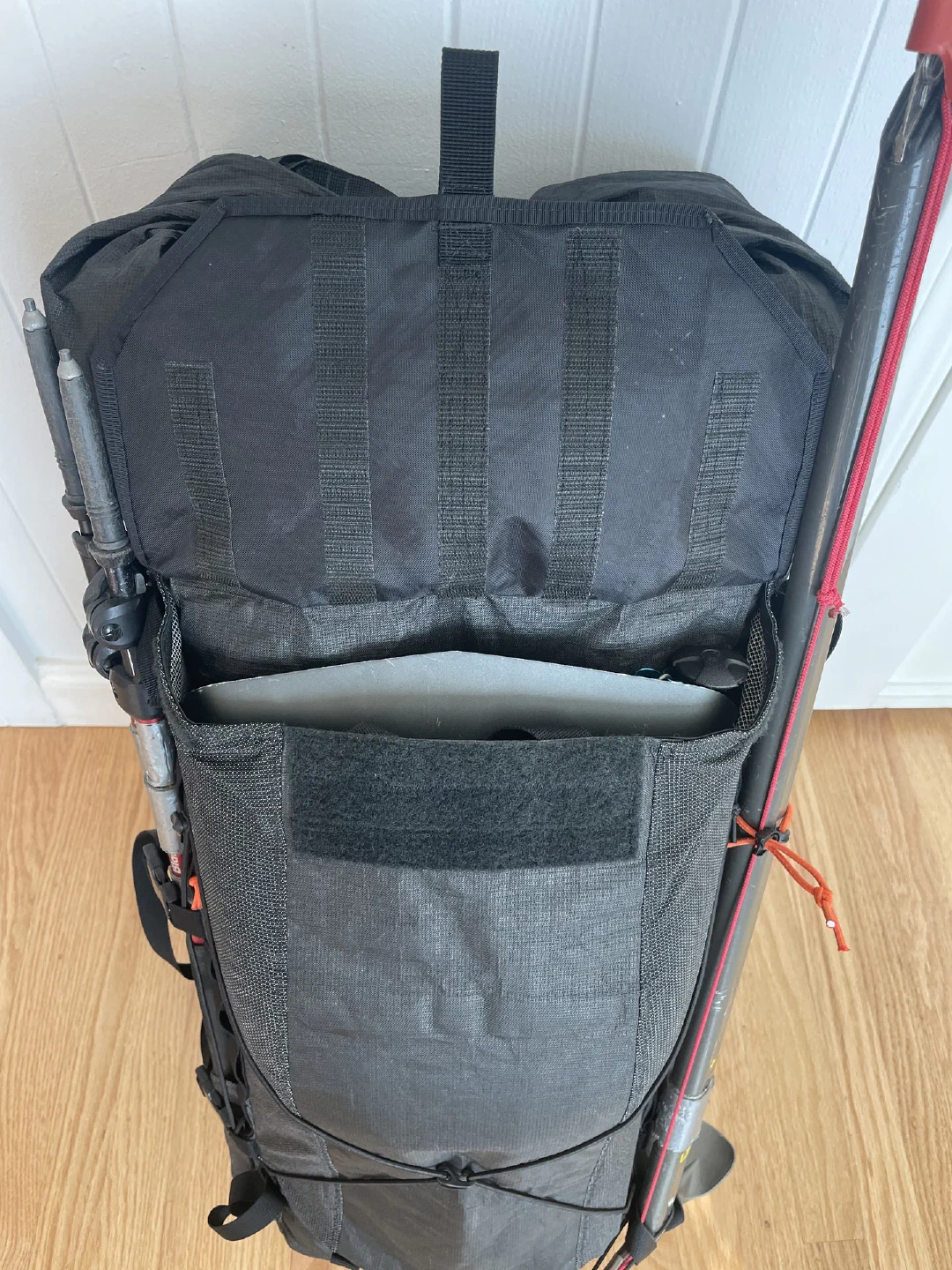 Front pocket loaded with avalanche tools, ice axe and poles attached at sides.