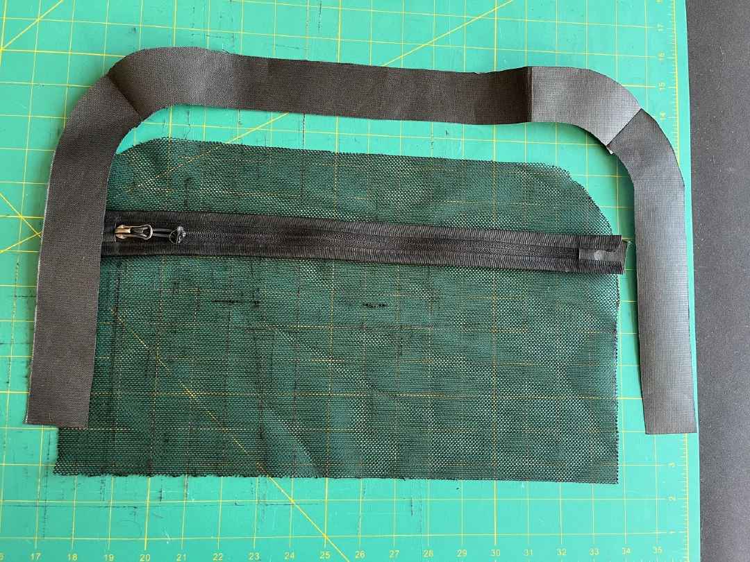 A zip set into a pocket panel, binding strips alongside on the cutting mat