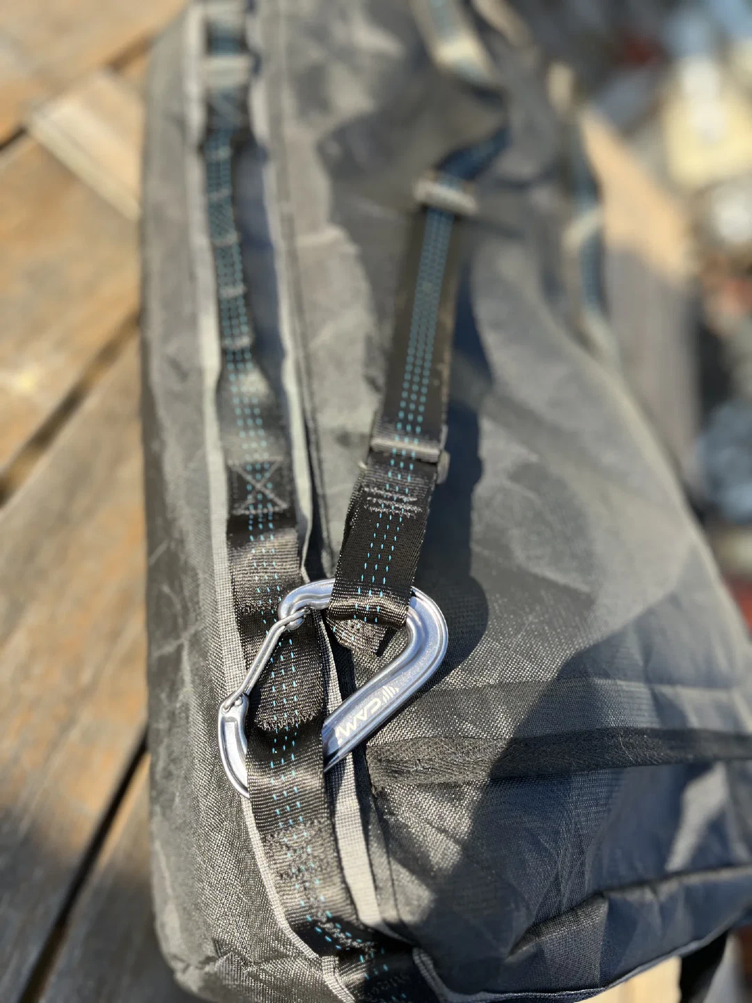 A carabiner clipped to the strap anchor, triple-stitched webbing below