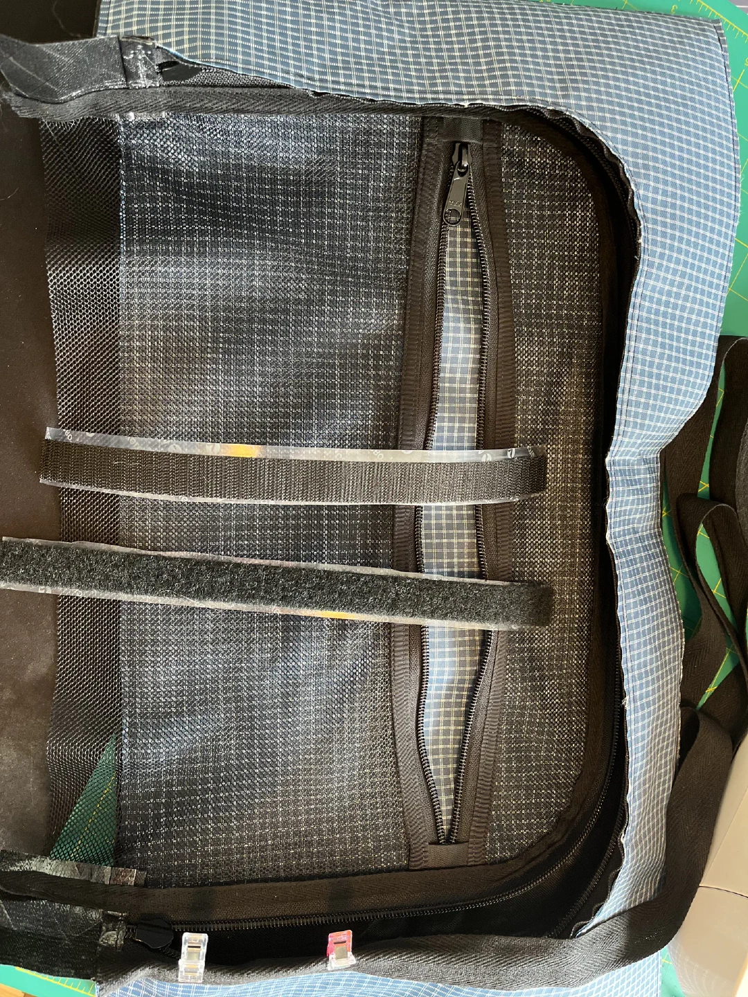 Lid interior mid-build: a zippered mesh pocket on the blue liner, two hook-and-loop strips across